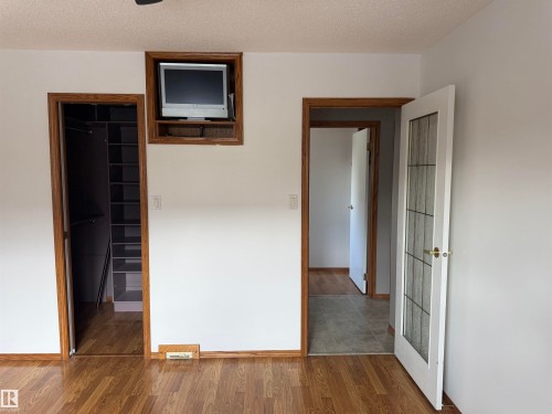 Wood-finish flooring throughout, complemented by white walls and wood-trimmed doorways - 1412 63 Street Nw, Edmonton, AB 