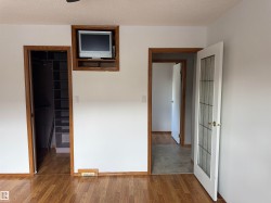 Wood-finish flooring throughout, complemented by white walls and wood-trimmed doorways - 