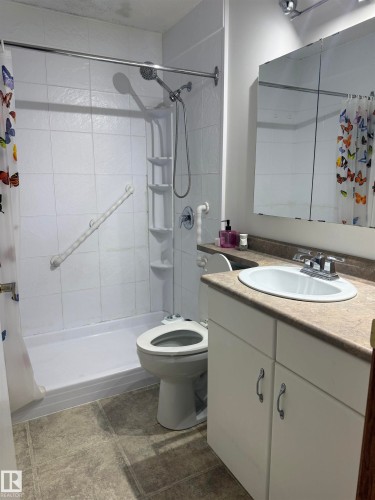 White tiled shower with a handheld showerhead, grab bars, and an integrated shelf - 1412 63 Street Nw, Edmonton, AB 