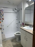 Shower-tub combination with white tile surround, single vanity with integrated sink, track lighting, and mirrored medicine cabinet - 
