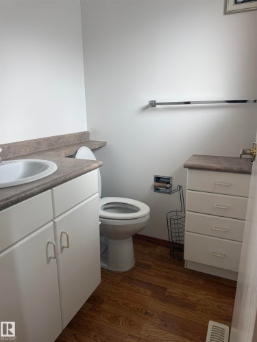 White vanity with integrated sink, wood-finish flooring, and a coordinating storage cabinet - 1412 63 Street Nw, Edmonton, AB 