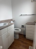 White vanity with integrated sink, wood-finish flooring, and a coordinating storage cabinet - 