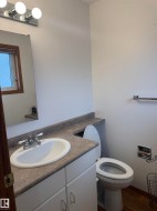 White vanity cabinet with an integrated sink, laminate countertop, and wood-finish flooring - 