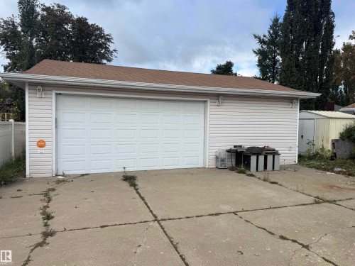 Two-car garage with a panel-style door, horizontal siding, and exterior lighting fixtures - 1412 63 Street Nw, Edmonton, AB 