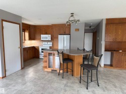 Kitchen featuring wood cabinetry, integrated appliances, an island with countertop seating, and tiled flooring - 