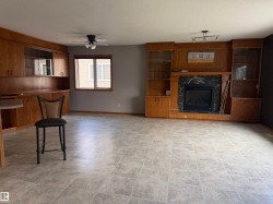 Built-in wood cabinetry with glass-front uppers, a fireplace with a stone surround, tiled flooring, and a ceiling fan - 