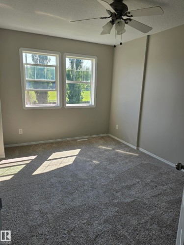 Room featuring two windows, neutral-toned walls, and a ceiling fan with integrated lighting - 4120 47 Street, Drayton Valley, AB - Indoor Photo Showing Other Room