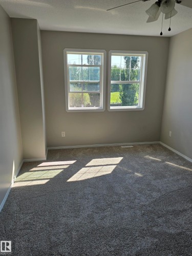 Carpeted interior space featuring two large windows, a ceiling fan with light fixture, light-toned walls, and white trim - 4120 47 Street, Drayton Valley, AB - Indoor Photo Showing Other Room