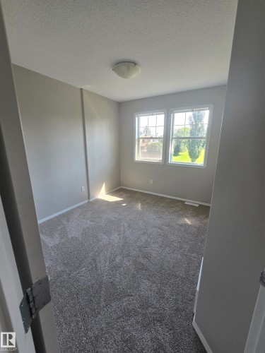 Spacious room featuring neutral carpeting, light gray walls, a flush-mount ceiling light, and two large windows - 4120 47 Street, Drayton Valley, AB - Indoor Photo Showing Other Room