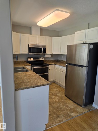 Kitchen featuring white cabinetry with silver hardware, stone-look countertops, and stainless steel appliances - 4120 47 Street, Drayton Valley, AB - Indoor Photo Showing Kitchen With Double Sink