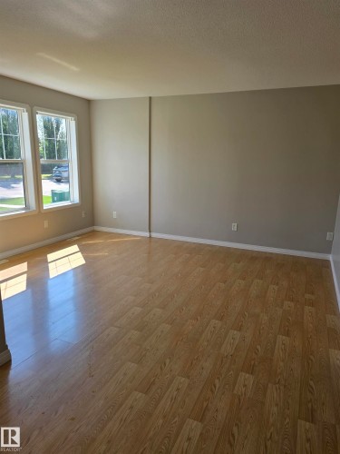 Expansive room featuring wood-finish flooring, light neutral wall tones, and white baseboards - 4120 47 Street, Drayton Valley, AB - Indoor Photo Showing Other Room