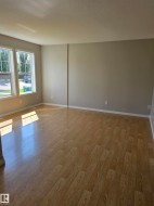 Expansive room featuring wood-finish flooring, light neutral wall tones, and white baseboards - 