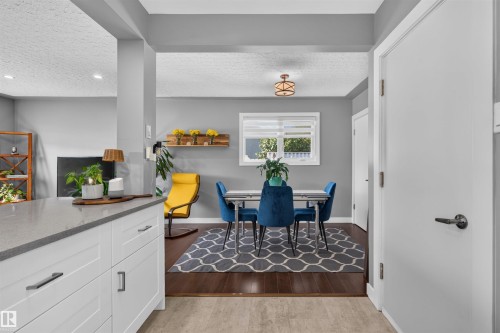 Open-concept dining area with wood-finish flooring, a contemporary light fixture, and a window providing natural illumination - 12136 135A Avenue Nw, Edmonton, AB - Indoor