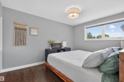 Bedroom featuring wood-finish flooring, light gray wall tones, and white baseboards - 