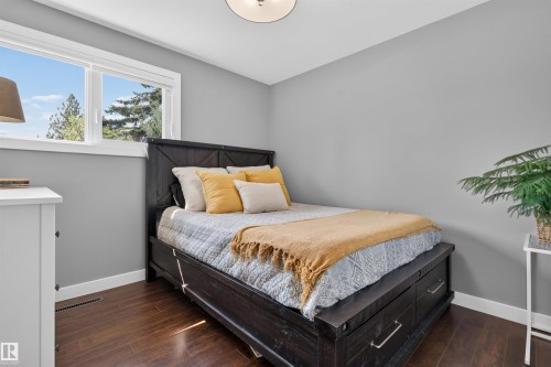 Bright room featuring a large window, dark wood-finish flooring, and light gray walls - 12136 135A Avenue Nw, Edmonton, AB - Indoor Photo Showing Bedroom