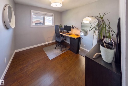 Spacious room featuring wood-finish flooring, light gray walls, and a window with white trim - 12136 135A Avenue Nw, Edmonton, AB - Indoor Photo Showing Office