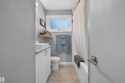 Bathroom featuring a white vanity with a rectangular vessel sink, light gray countertop, and contemporary hardware - 