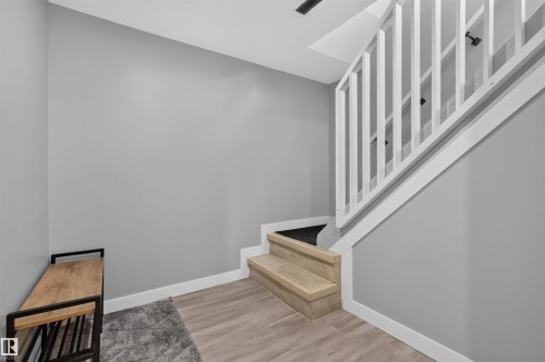 Staircase featuring wood-finish treads and a white balustrade, complemented by light gray walls and wood-finish flooring - 12136 135A Avenue Nw, Edmonton, AB - Indoor Photo Showing Other Room