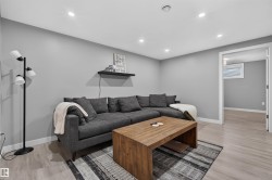 Recessed ceiling lighting illuminates a room with light wood-finish flooring and a flat black wall-mounted shelf - 