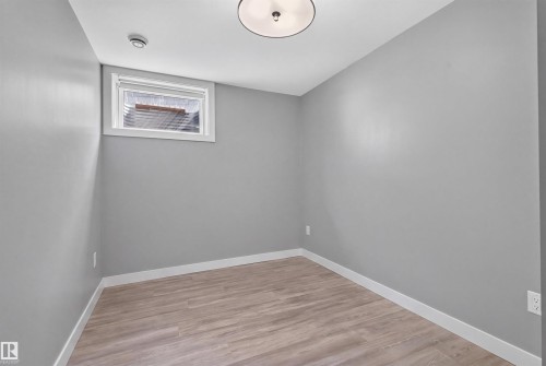 Room featuring light gray walls, wood-finish flooring, white baseboards, and a window with blinds - 12136 135A Avenue Nw, Edmonton, AB - Indoor Photo Showing Other Room