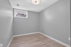 Room featuring light gray walls, wood-finish flooring, white baseboards, and a window with blinds - 