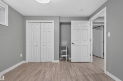 Room featuring neutral gray walls, wood-finish flooring, white trim, and a bi-fold closet with panel doors - 