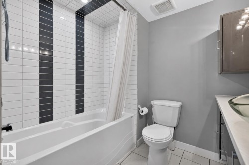 Full bathroom featuring a white soaking tub with subway tile surround, accented by two vertical black tile strips - 12136 135A Avenue Nw, Edmonton, AB - Indoor Photo Showing Bathroom