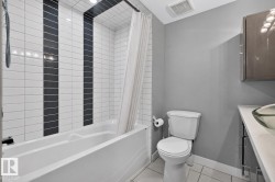 Full bathroom featuring a white soaking tub with subway tile surround, accented by two vertical black tile strips - 
