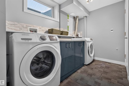 Dedicated laundry area featuring a window, built-in cabinetry, countertops, and a full-height backsplash - 12136 135A Avenue Nw, Edmonton, AB - Indoor Photo Showing Laundry Room