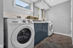 Dedicated laundry area featuring a window, built-in cabinetry, countertops, and a full-height backsplash - 