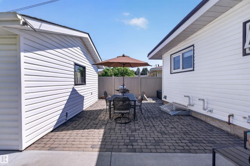 Paved patio area featuring interlocking pavers, white siding, and a privacy fence - 12136 135A Avenue Nw, Edmonton, AB - Outdoor With Exterior