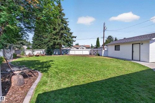 Spacious backyard featuring a manicured lawn, white privacy fencing, and mature trees - 12136 135A Avenue Nw, Edmonton, AB - Outdoor