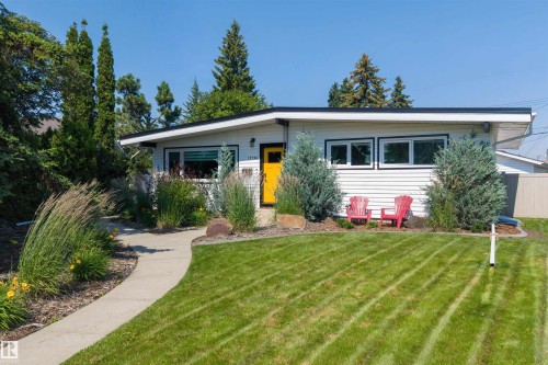 White siding exterior with a contrasting black roofline and a vibrant yellow front door - 12136 135A Avenue Nw, Edmonton, AB - Outdoor