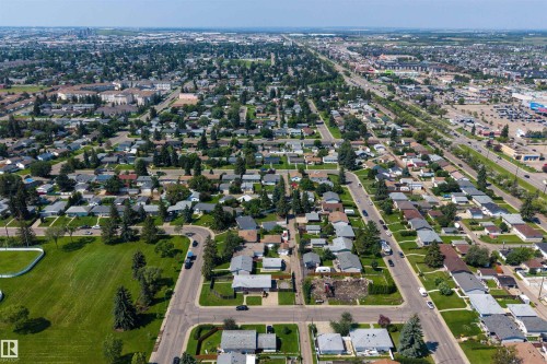 Expansive aerial perspective showcasing a residential neighborhood with detached homes, mature trees, and a manicured green space - 12136 135A Avenue Nw, Edmonton, AB - Outdoor With View