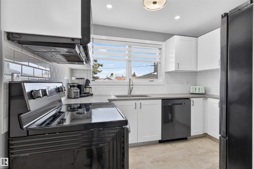 Modern kitchen featuring white shaker cabinetry, light-toned countertops, and a white subway tile backsplash - 12136 135A Avenue Nw, Edmonton, AB - Indoor Photo Showing Kitchen With Double Sink