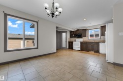Open-concept space featuring ceramic tile flooring, a kitchen with dark wood-finish cabinetry, and white appliances - 
