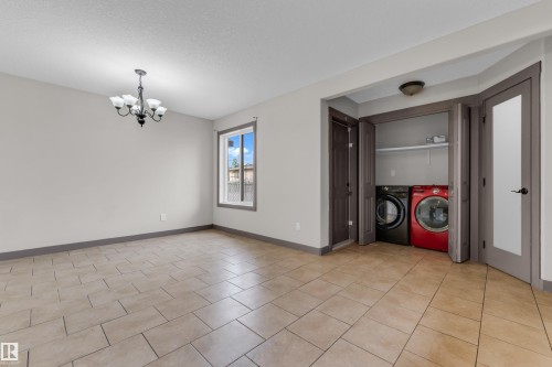 Spacious room featuring tile flooring, a window with exterior views, and a multi-light chandelier - 11817 37 Street Nw, Edmonton, AB - Indoor