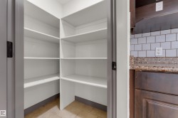 Corner pantry featuring multiple white shelves and tile flooring - 