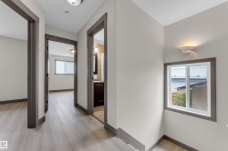 Hallway with wood-finish flooring, white walls, and dark trim - 