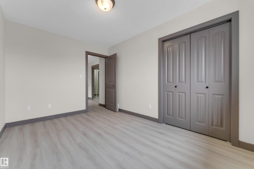 Neutral-toned room featuring light wood-finish flooring, a bi-fold closet with panel detailing, and a matching doorway - 11817 37 Street Nw, Edmonton, AB - Indoor Photo Showing Other Room