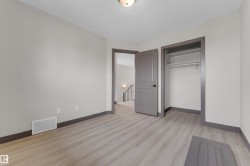 Spacious room featuring light wood-finish flooring, neutral gray walls, a built-in closet with shelving and hanging rod, and a coordinating gray paneled door - 