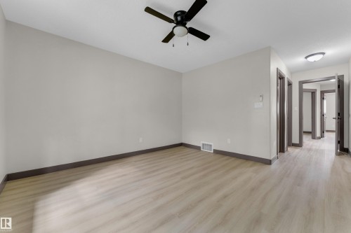 Spacious room with light wood-finish flooring, light gray wall paint, and contrasting dark baseboards - 11817 37 Street Nw, Edmonton, AB - Indoor Photo Showing Other Room