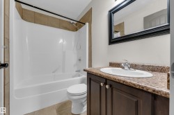 Bathroom vanity featuring a dark wood-finish cabinet with double doors and knob hardware, paired with a speckled countertop and an oval undermount sink - 