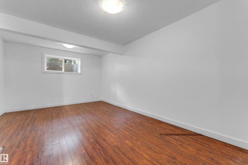 Room featuring wood-finish flooring, white walls, and a recessed window with horizontal blinds - 11817 37 Street Nw, Edmonton, AB - Indoor Photo Showing Other Room