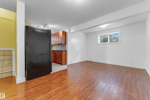 Open-concept living area featuring wood-finish flooring, white walls, and a window with white blinds - 11817 37 Street Nw, Edmonton, AB - Indoor Photo Showing Other Room