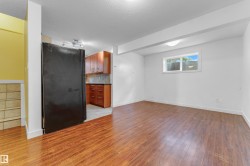 Open-concept living area featuring wood-finish flooring, white walls, and a window with white blinds - 