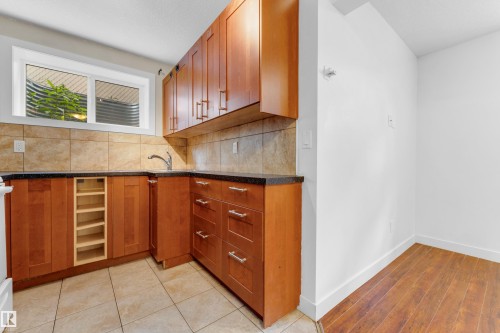 U-shaped kitchen with wood-finish cabinetry, dark countertops, and a tile backsplash - 11817 37 Street Nw, Edmonton, AB - Indoor
