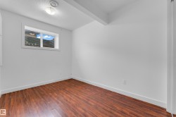 Room featuring wood-finish flooring, white walls, and a window with a white frame - 