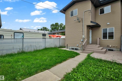 Rear exterior featuring neutral-toned horizontal siding, a multi-tiered deck with stairs, and a concrete patio - 11817 37 Street Nw, Edmonton, AB - Outdoor