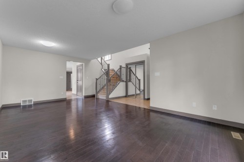 Expansive room featuring dark wood-finish flooring, light-toned walls, and a visible air vent - 11817 37 Street Nw, Edmonton, AB - Indoor Photo Showing Other Room